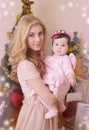 Mother and dressed like angel baby girl at Christmas tree