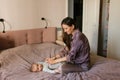 Mother dressing her newborn baby son lying on bed Royalty Free Stock Photo