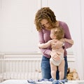 Mother dressing her son in bedroom