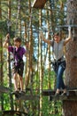 Mother and eight year old son surmounting obstacle course in the outdoor woodland rope park. Active family rest