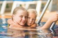 Mother embraces daughter near ladder in pool in tropical beach r