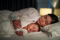 mother embraces the infant baby sleeping together in bed at night Royalty Free Stock Photo