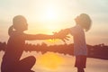 Mother encouraged her son outdoors at sunset, silhouette concept Royalty Free Stock Photo