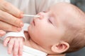 Mother ensures her newborn's nose is free from obstructions using a soft cotton stick