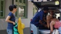 Mother and family friends putting voyage baggage in car