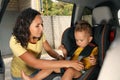 Mother fastening her son with car safety belt in child seat Royalty Free Stock Photo