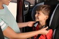 Mother fastening her son with car safety belt in child seat Royalty Free Stock Photo