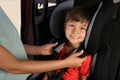 Mother fastening her son with car safety belt in child seat Royalty Free Stock Photo