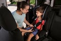 Mother fastening her son with car safety belt in child seat Royalty Free Stock Photo