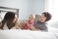 Mother father and baby child on a white bed. Royalty Free Stock Photo