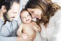 Mother father and baby child on a white bed. Royalty Free Stock Photo