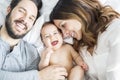Mother father and baby child on a white bed. Royalty Free Stock Photo