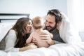 Mother father and baby child on a white bed. Royalty Free Stock Photo