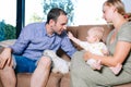 Mother, father, baby and dog. Happy family sitting on the sofa at home Royalty Free Stock Photo