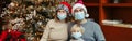 Mother, father, baby girl in Santa hats and face masks celebrating Christmas holiday at home. Holiday family celebration during Royalty Free Stock Photo