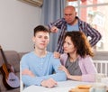 Mother and father berating frowning teen boy