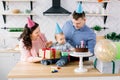 Mother and father in birthday hats celebrating first birthday of baby boy at home kitchen. Happy family celebrating Royalty Free Stock Photo