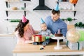 Mother and father in birthday hats celebrating first birthday of baby boy at home kitchen. Happy family celebrating Royalty Free Stock Photo