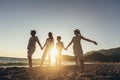 Mother, father and children holding hands enjoying the sunset on the beach. Royalty Free Stock Photo