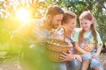 Mother and father with daughter are collecting eggs and putting them in a brown wicker baset, concept organic family lifestyle