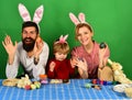 Mother, father and daughter painting eggs in pink bunny ears Royalty Free Stock Photo