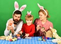 Mother, father and daughter painting eggs in pink bunny ears Royalty Free Stock Photo