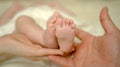 Mother and father hold newborn baby bare feet. Tiny feet in woman hand. Cozy morning at home. Love and family concept. Royalty Free Stock Photo