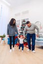 Mother and father holding their cute baby by hands and teaching him how to walk in the middle of the christmas decorated Royalty Free Stock Photo