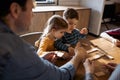 Mother, father and kids are playing dominoes while sitting in the the living room near the window Royalty Free Stock Photo