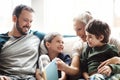 Mother, father and kids on sofa for storytelling time in living room of happy family home. Love, books and couple with