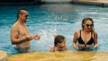 The mother and father with little daughter have fun in the pool. Mom and dad plays with the child. The family enjoy Royalty Free Stock Photo