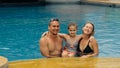 The mother and father with little daughter have fun in the pool. Mom and dad plays with the child. The family enjoy Royalty Free Stock Photo