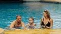 The mother and father with little daughter have fun in the pool. Mom and dad plays with the child. The family enjoy Royalty Free Stock Photo