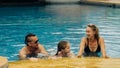 The mother and father with little daughter have fun in the pool. Mom and dad plays with the child. The family enjoy Royalty Free Stock Photo