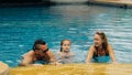 The mother and father with little daughter have fun in the pool. Mom and dad plays with the child. The family enjoy Royalty Free Stock Photo