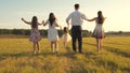Mother, father and little daughter with sisters walking in field in the sun. Happy young family. Children, dad and mom Royalty Free Stock Photo