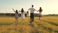 Mother, father and little daughter with sisters walking in field in the sun. Happy young family. Children, dad and mom Royalty Free Stock Photo