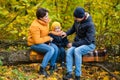 Mother, father and little son sit on a plaid on a log in the autumn park and spend time together Royalty Free Stock Photo