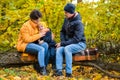 Mother, father and little son sit on a plaid on a log in the autumn park and spend time together Royalty Free Stock Photo