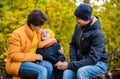 Mother, father and little son sit on a plaid on a log in the autumn park and spend time together Royalty Free Stock Photo