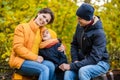 Mother, father and little son sit on a plaid on a log in the autumn park and spend time together Royalty Free Stock Photo