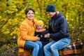 Mother, father and little son sit on a plaid on a log in the autumn park and spend time together Royalty Free Stock Photo