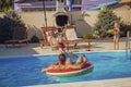 Mother and father playing with their children with water guns at the swimming pool Royalty Free Stock Photo