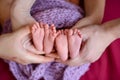 Mother and father`s hands cradling twin babies feet