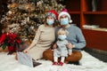 Mother and father in Santa hats and face masks with baby girl calling family on a video call. Distant remote holiday celebration Royalty Free Stock Photo