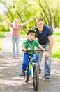 Mother and father teaches his son to ride a bike