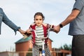 Mother and father teaches and supporting little child daughter ride bike outdoor. Happy family Royalty Free Stock Photo
