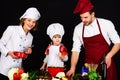 Mother and father teaching son to cook. Happy family in chef uniform preparing breakfast, dinner or supper. Healthy food Royalty Free Stock Photo