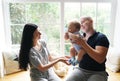 Mother, father and their baby son having fun and playing at home near a big window with sunlight Royalty Free Stock Photo