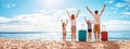 Mother and father with their children standing on the beach with suitcases.